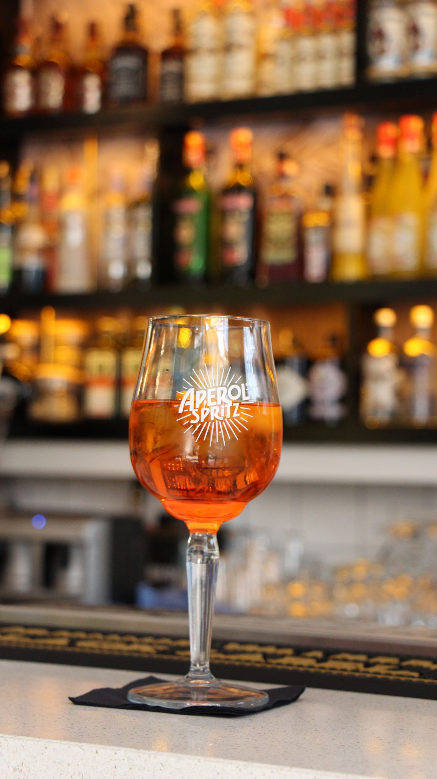 Orange spritz-style drink in a stemmed glass at a bar