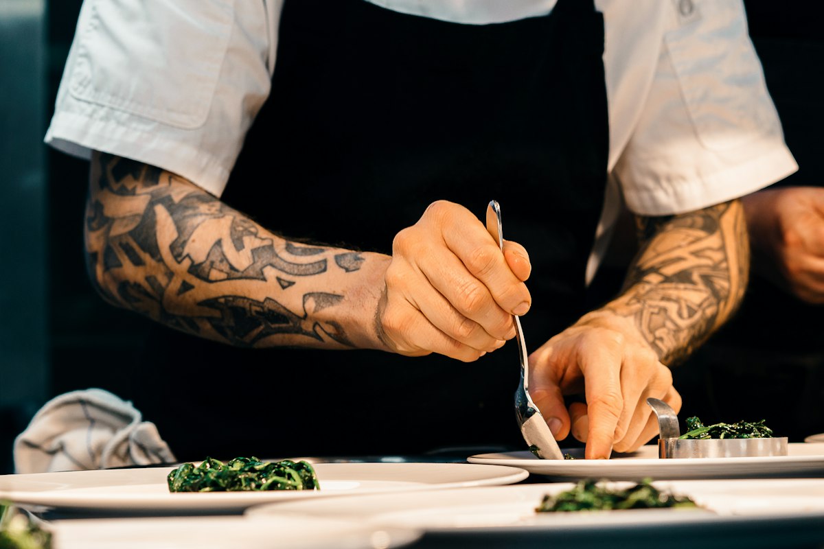 Chef carefully placing garnish on plates at the kitchen counter