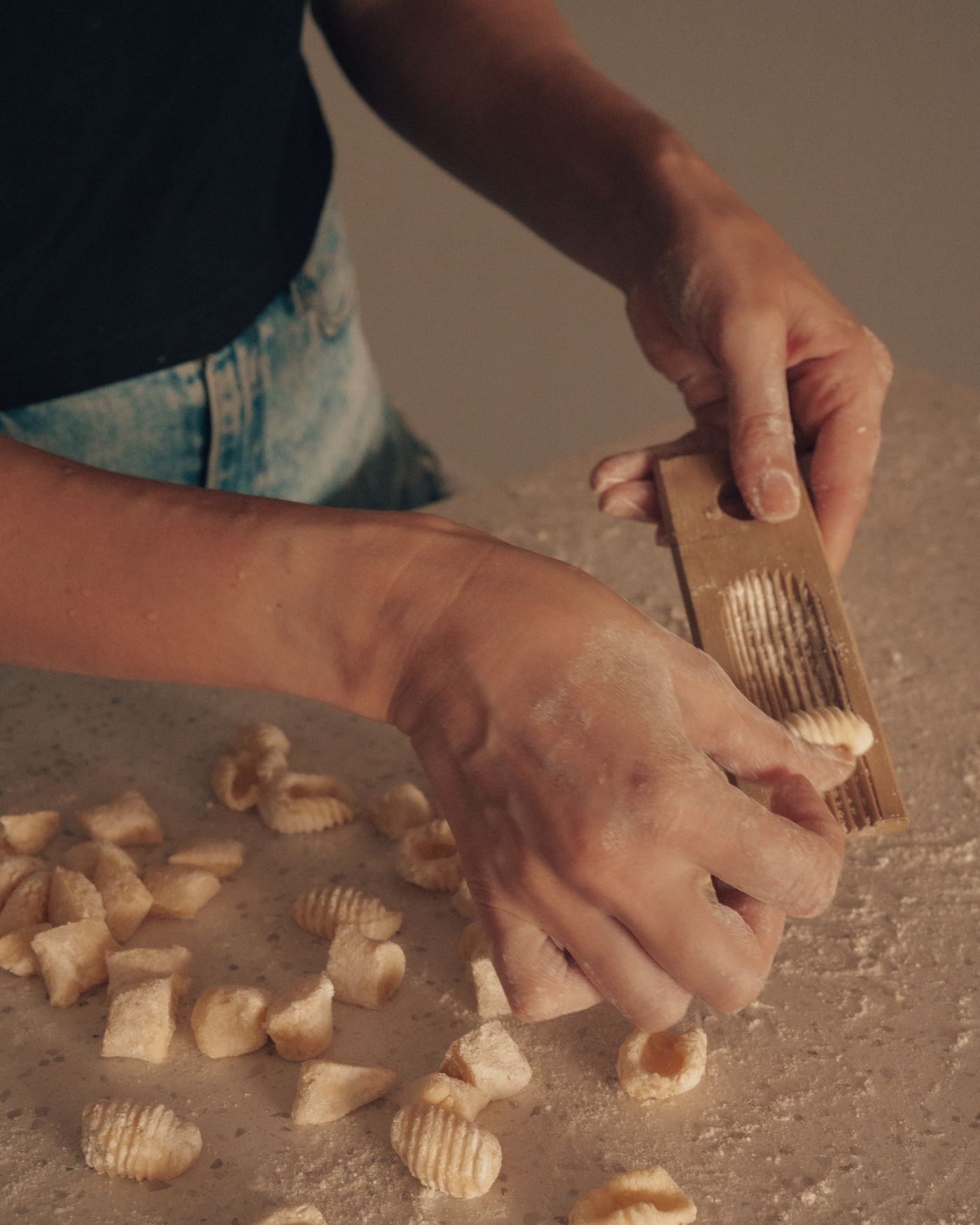 Hands shaping fresh gnocchi on a floured counter