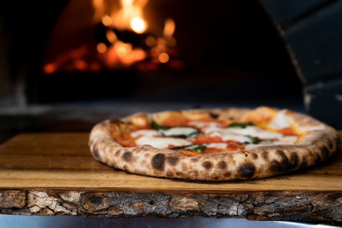 Wood-fired pizza with leopard-spotted crust on a wooden board