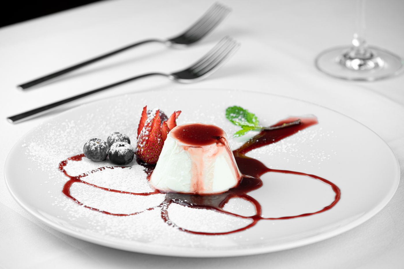 Panna cotta with fresh berries and mint on a white plate