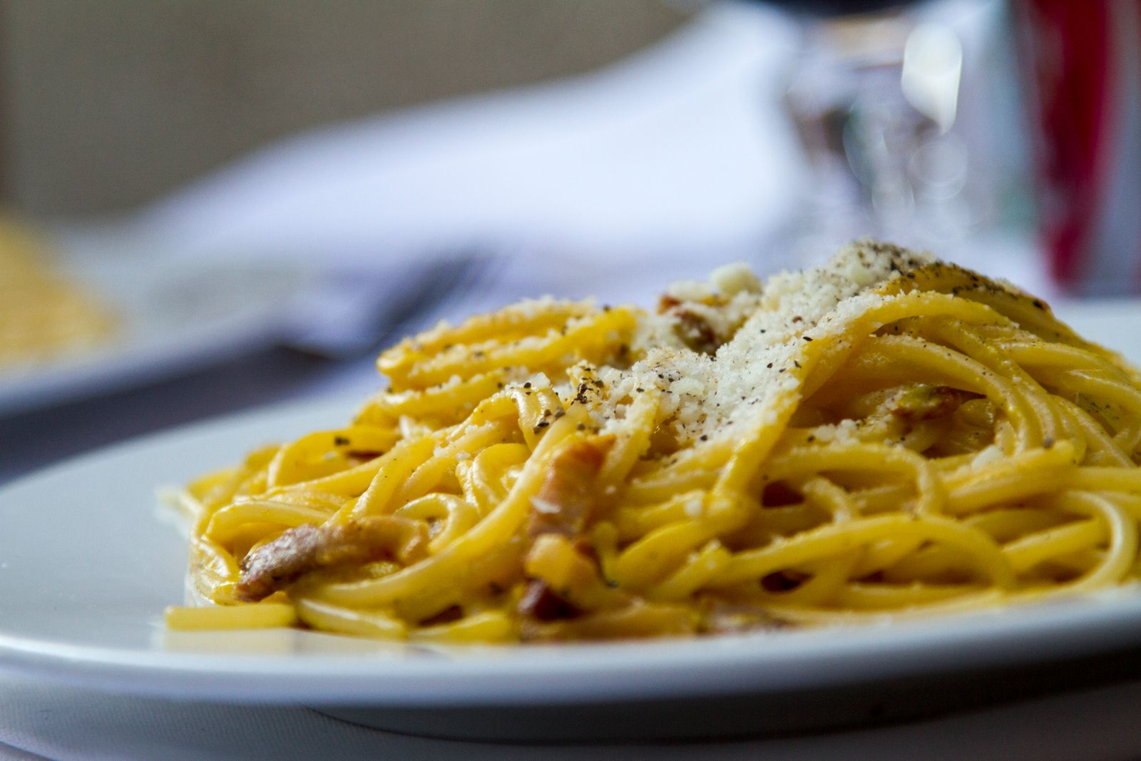 Spaghetti carbonara topped with grated cheese and black pepper